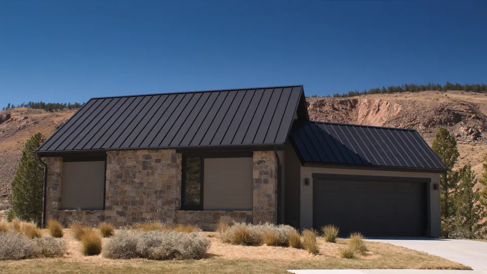 Home with a dark standing seam metal roof below a sandstone hogback in the Colorado Front Range foothills