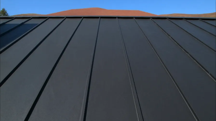 Raised seams running up a dark standing seam metal roof toward the ridge cap